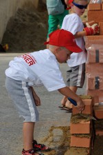 ein süßes Kind beim Mauern auf der Kinderbaustelle